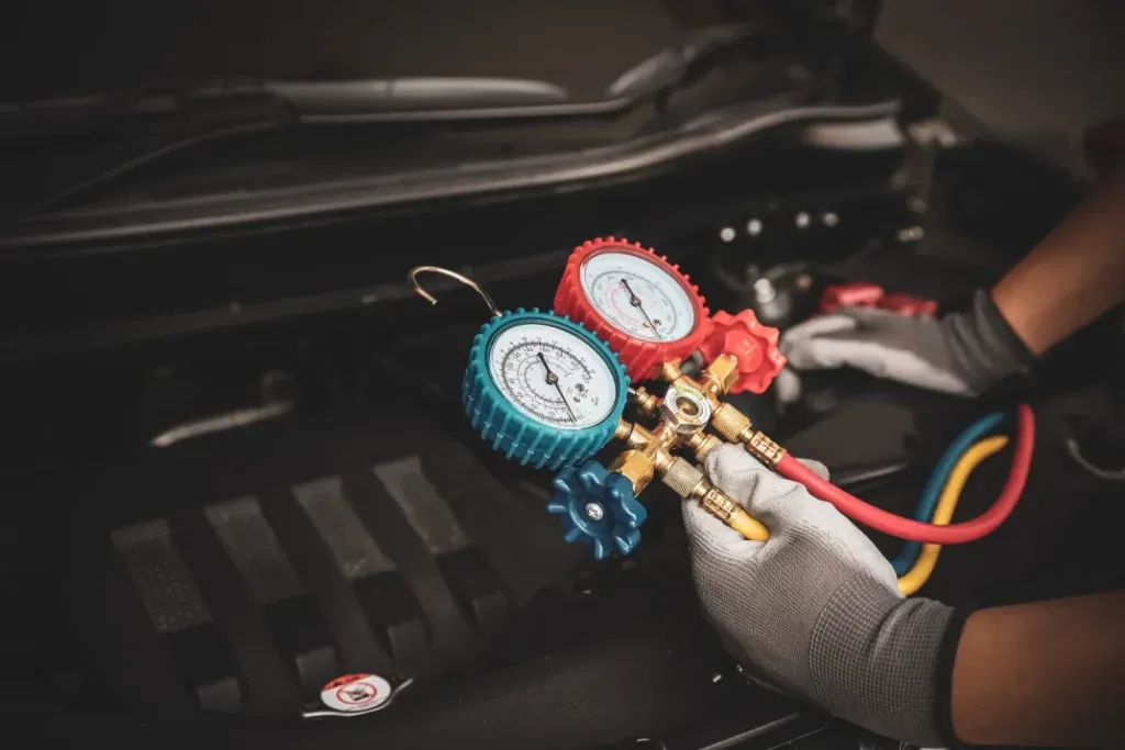 Gloved hands of Epoch Mechanic adjusting A/C gauges used for diagnosing or recharging an automotive air conditioning unit in Doylestown, PA