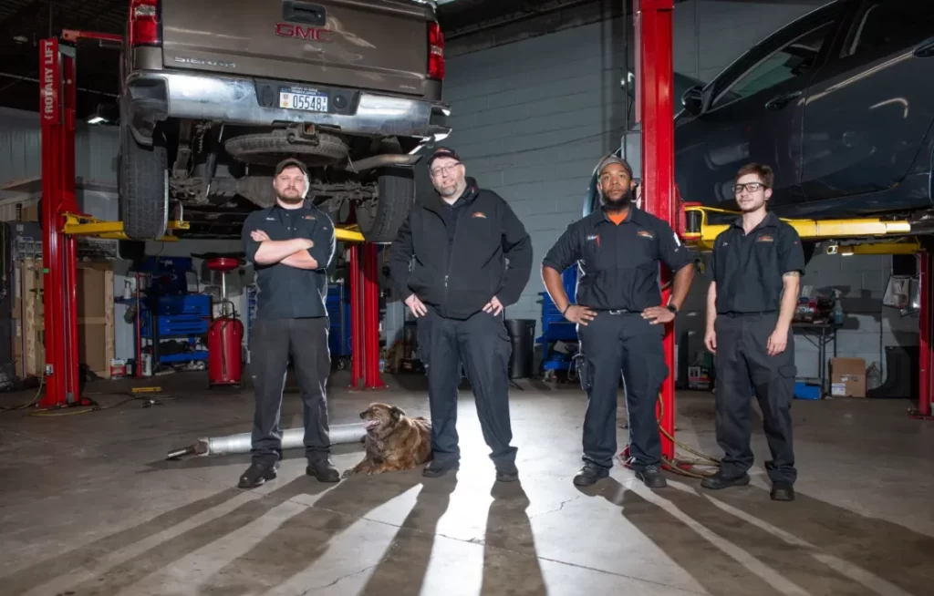 Four mechanics and a dog in Doylestown, PA pose in a garage with cars on lifts