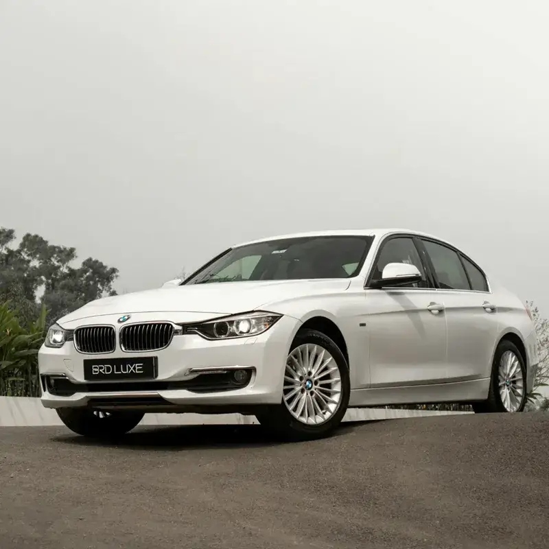 White BMW sedan parked on an incline with a cloudy sky in the background