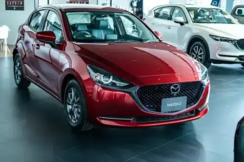 New red Mazda compact car shown under showroom lighting with a visible nameplate