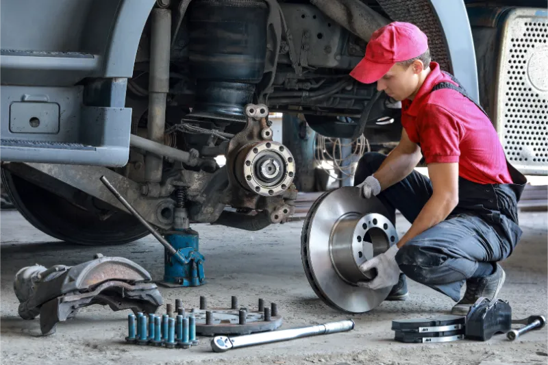 Epoch technician in red uniform prepares to install a brake rotor on a raised vehicle with the wheel removed in Doylestown. PA